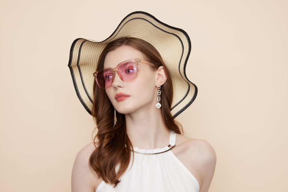 Portrait of a stylish woman wearing pink sunglasses and a wide-brimmed hat, exuding elegance and modern fashion.