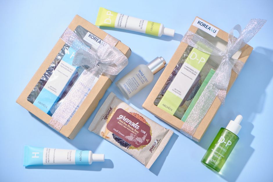 A neatly arranged beauty gift set including moisturiser, serum and lip balm on a white surface, perfect as a summer gift for her