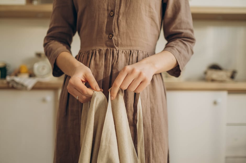 Woman wearing a flowing linen midi dress in a neutral sand tone, styled with sandals