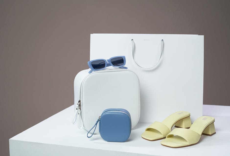 Flat lay of summer accessories including strappy sandals, a rattan bag, and gold jewellery on a white background