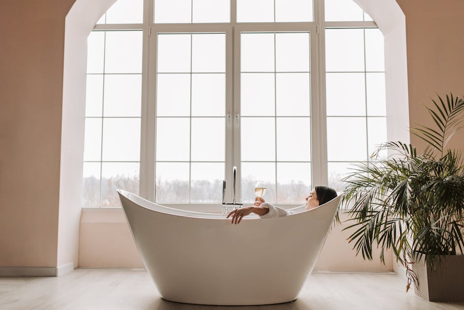 Minimalist spa-style bathroom with rolled white towels, green plant and wooden accessories