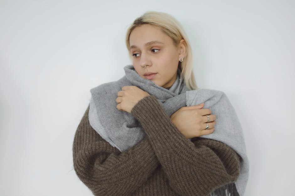 A folded soft cashmere scarf in a neutral camel colour on a wooden surface