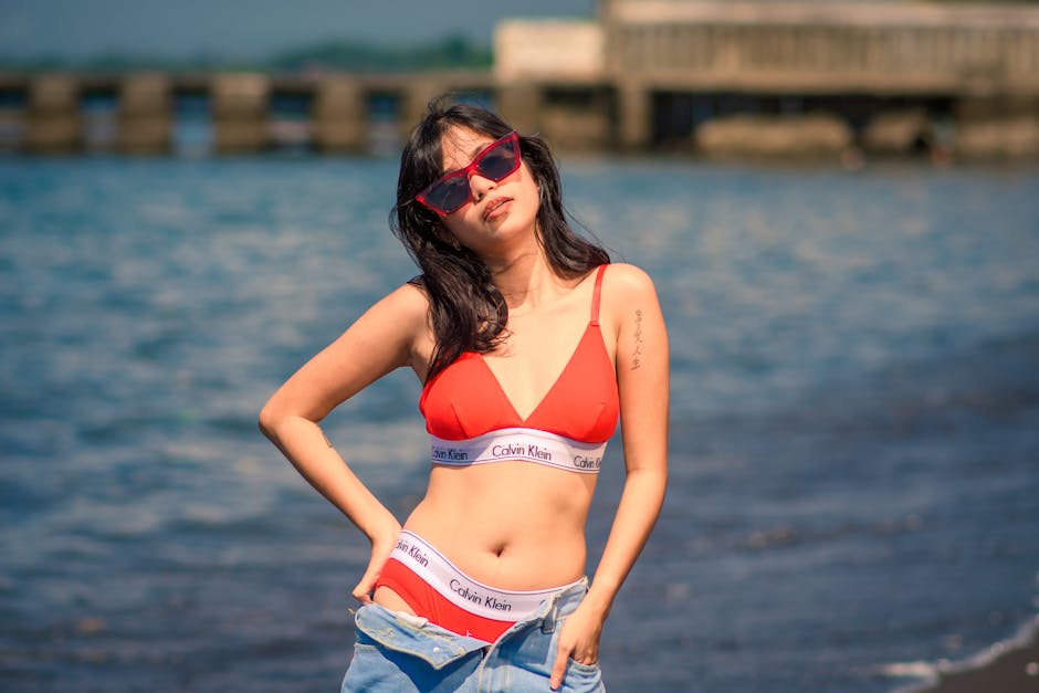 Model wearing minimalist Calvin Klein swimwear beside a pool, representing the brand's clean summer aesthetic
