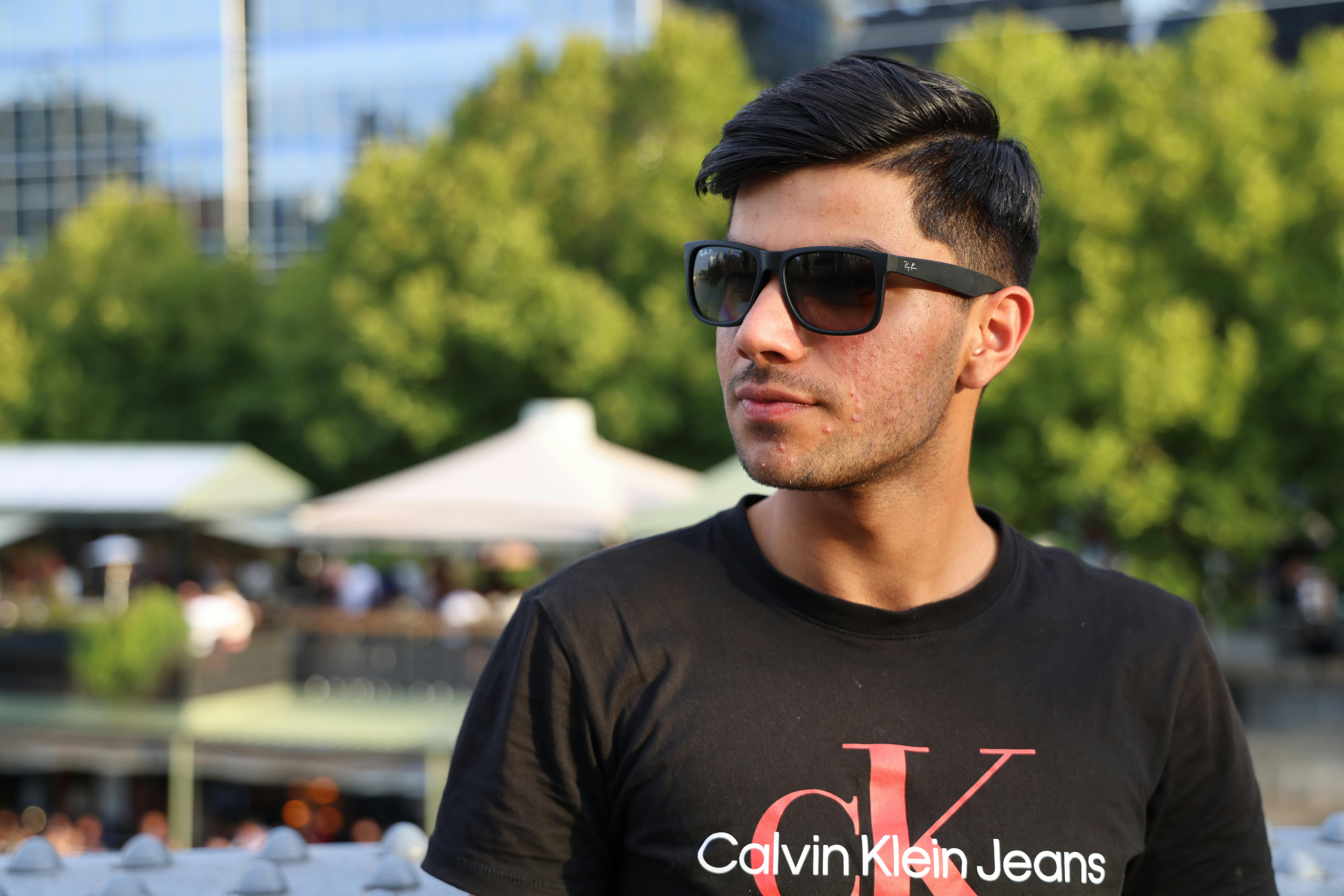 Portrait of a man wearing sunglasses and a Calvin Klein T-shirt outdoors.