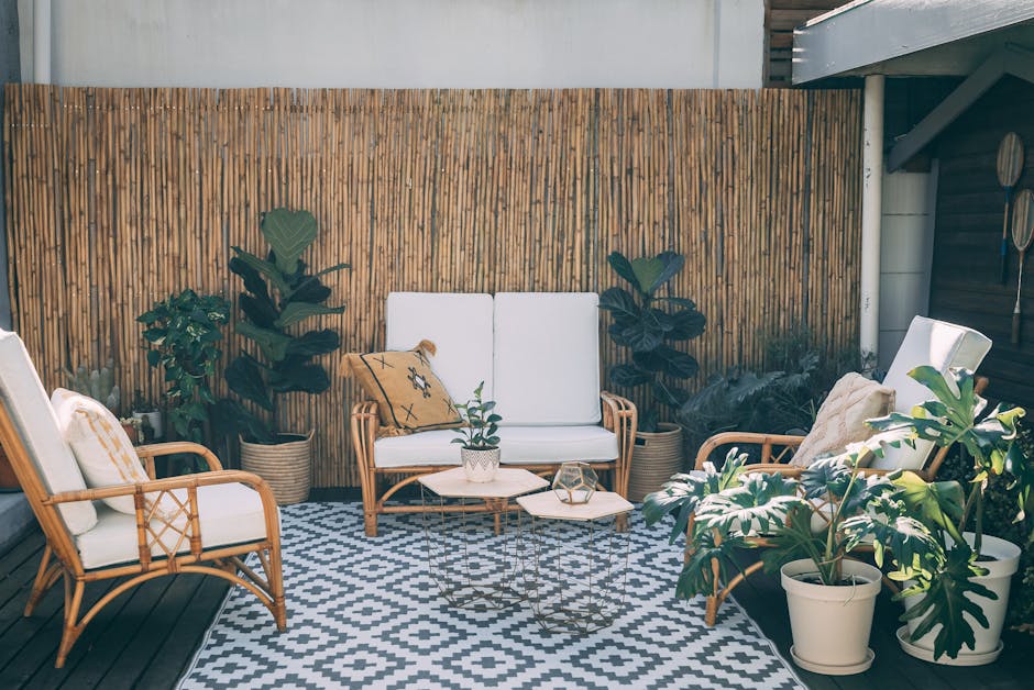 Rattan garden chairs and a low coffee table styled with outdoor lanterns and a knitted throw on a patio