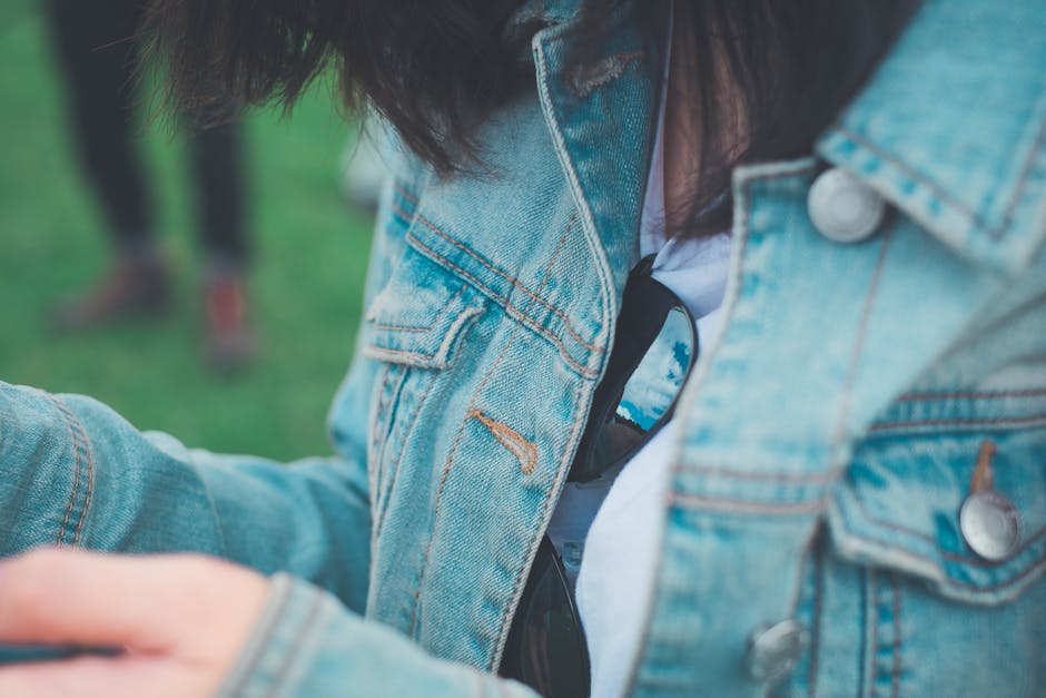 Woman styling an oversized denim jacket as part of a layered festival outfit outdoors