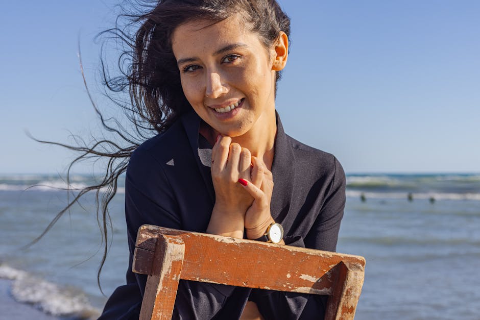 Woman with colour-treated hair enjoying a sunny beach day, hair blowing in the sea breeze