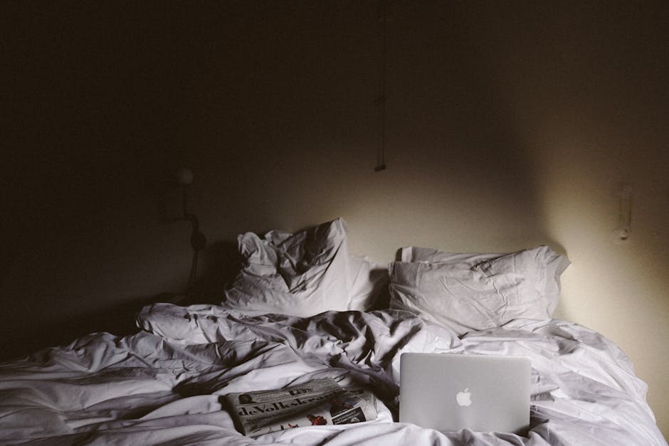 Neatly made bed with white linen sheets and a lightweight summer duvet in a minimal bedroom