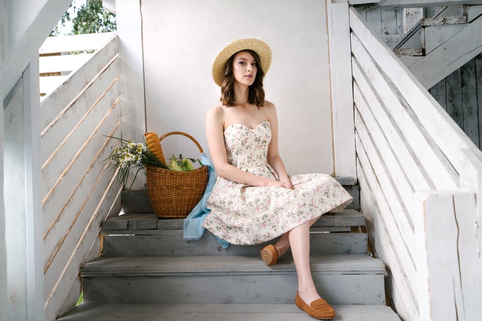 A woman wearing a vibrant floral midi dress outdoors in summer sunlight, reflecting summer 2026 dress trends