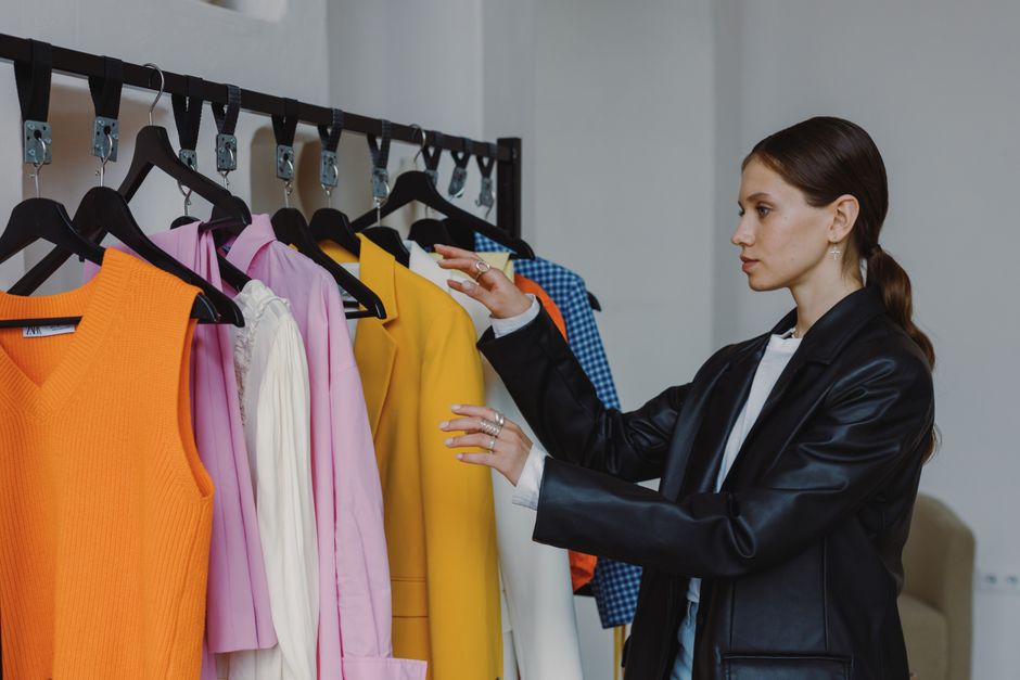 A woman browsing a rail of designer summer clothes, symbolising smart wardrobe planning and designer discounts
