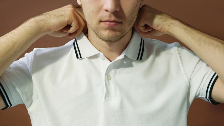 A classic white Fred Perry polo shirt with laurel wreath logo laid flat on a wooden surface
