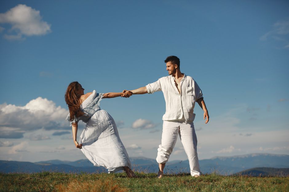 A man wearing a relaxed cream linen shirt and linen trousers outdoors on a warm summer day