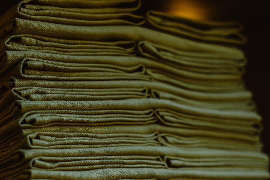 Close-up of neatly folded natural linen fabric showing its characteristic slub texture and earthy tone
