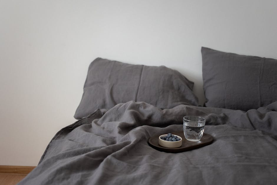 Neatly styled bed dressed in natural linen bedding in a bright, airy summer bedroom