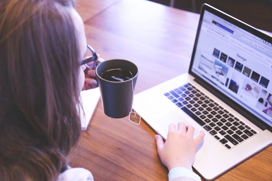 Person browsing luxury brands on a laptop with a coffee beside them
