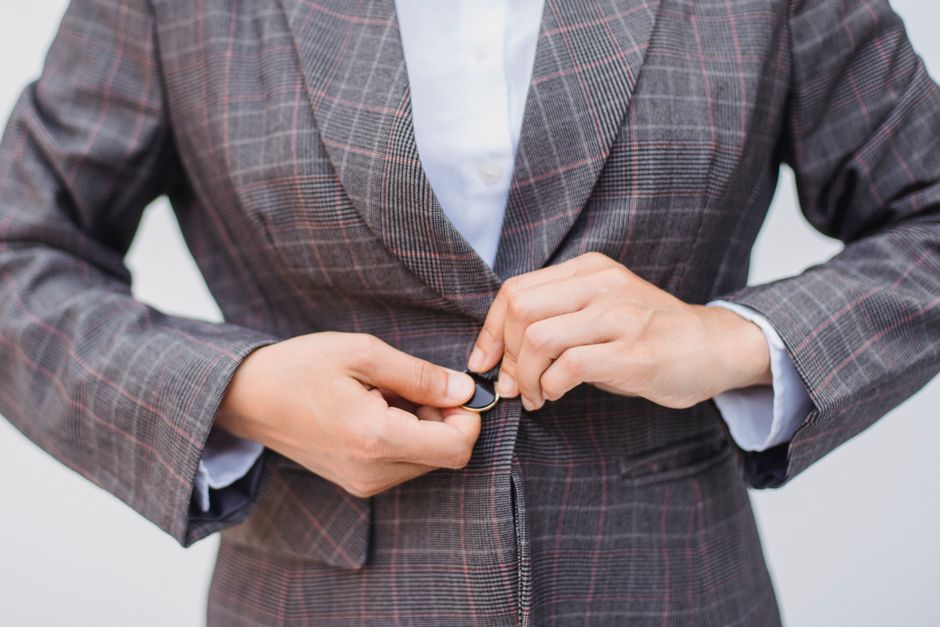 A woman wearing a sharp tailored blazer in a contemporary editorial setting