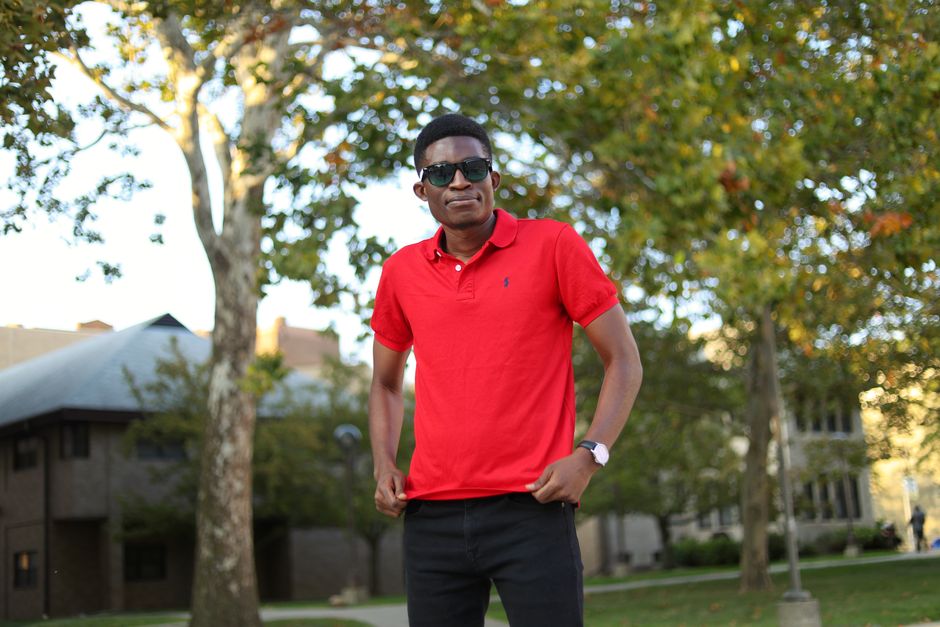 African man wearing sunglasses and red polo shirt standing in a park in Detroit, MI.