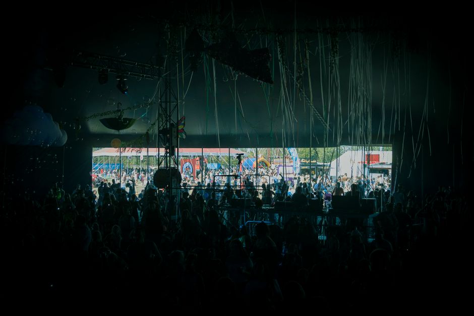 Colourful festival crowd at a UK summer music festival, people dressed in layered outfits and wellies