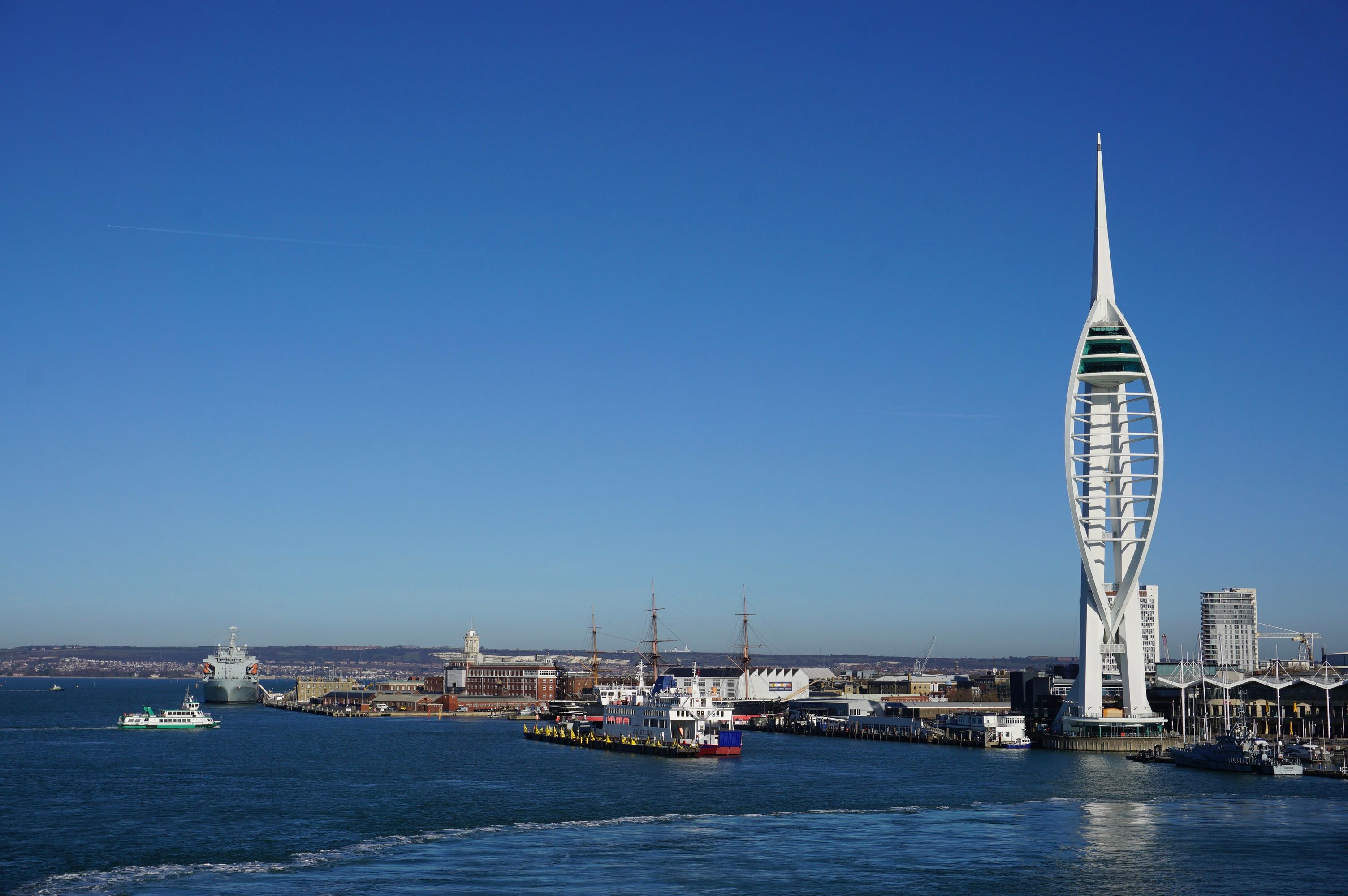 A vibrant view of the iconic Spinnaker Tower and bustling Portsmouth Harbour under a clear blue sky.