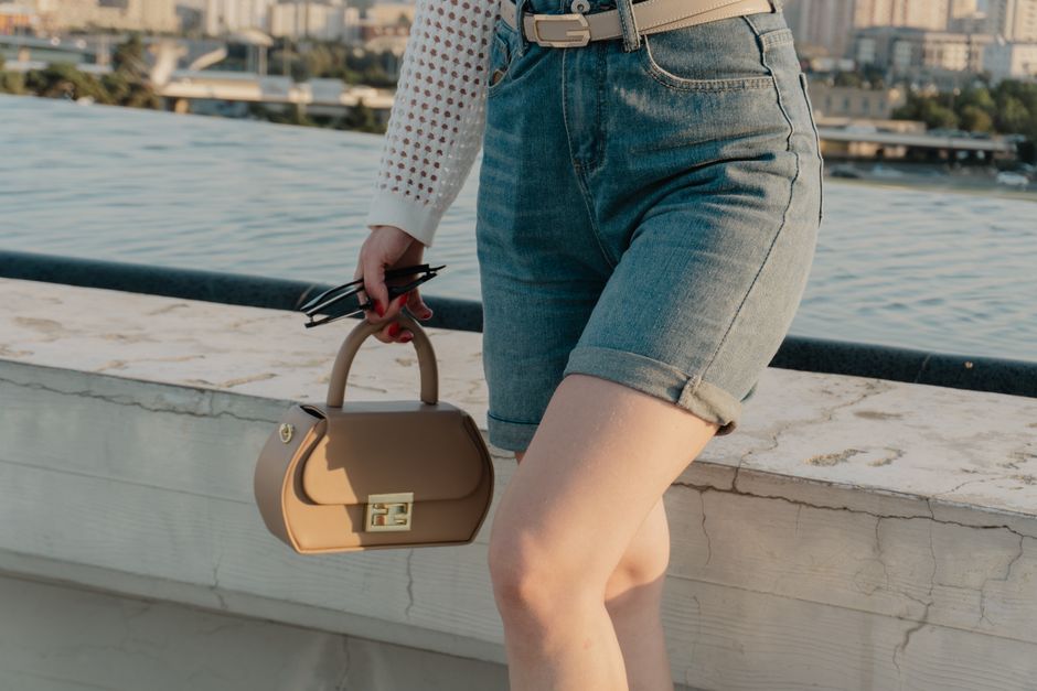 Folded light-wash denim shorts on a bright summer background