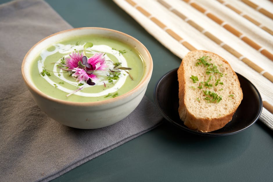 A bowl of chilled gazpacho soup garnished with cucumber and olive oil on a wooden table