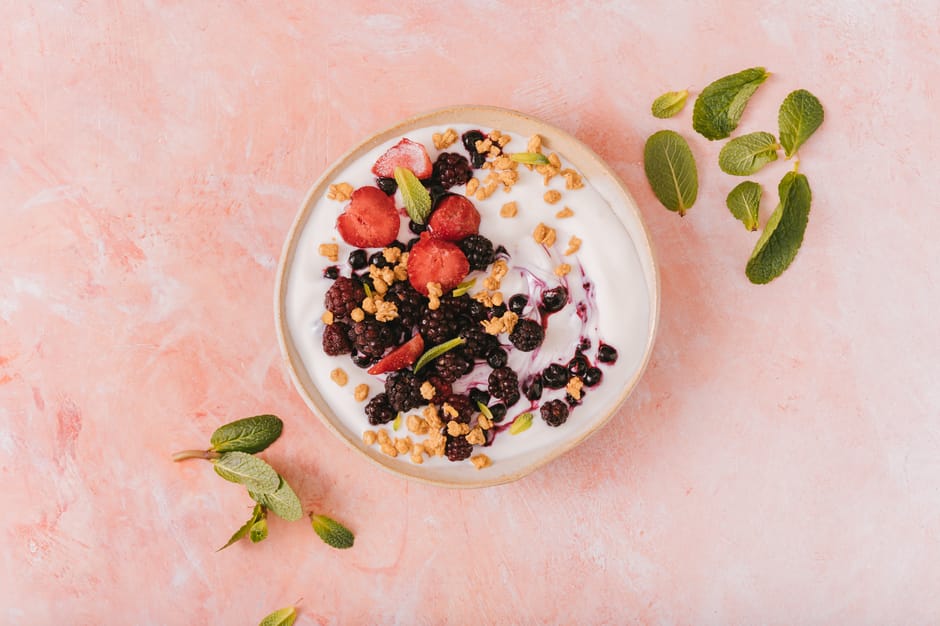Frozen yoghurt bark topped with fresh berries and honey on a marble surface