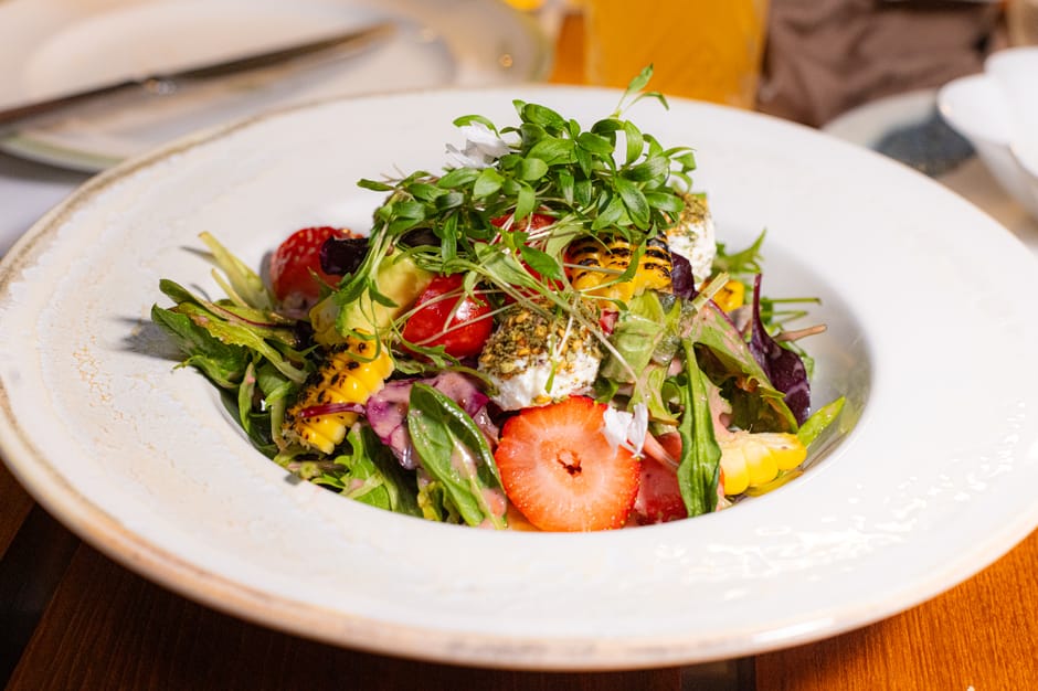 A vibrant fresh summer salad with colourful vegetables and herbs on a white table