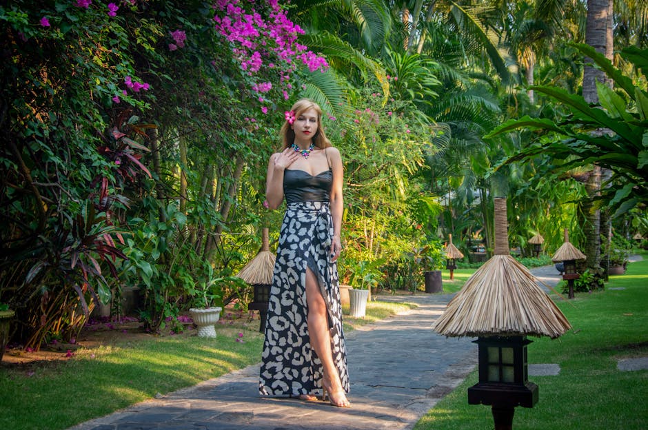 Woman wearing a Ted Baker-style floral resort dress on a sun-drenched terrace, styled with strappy sandals