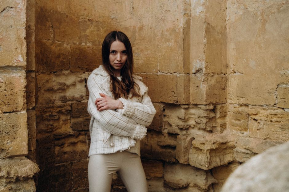 Editorial flat lay of warm neutral clothing including oat linen and terracotta knitwear with tan leather accessories