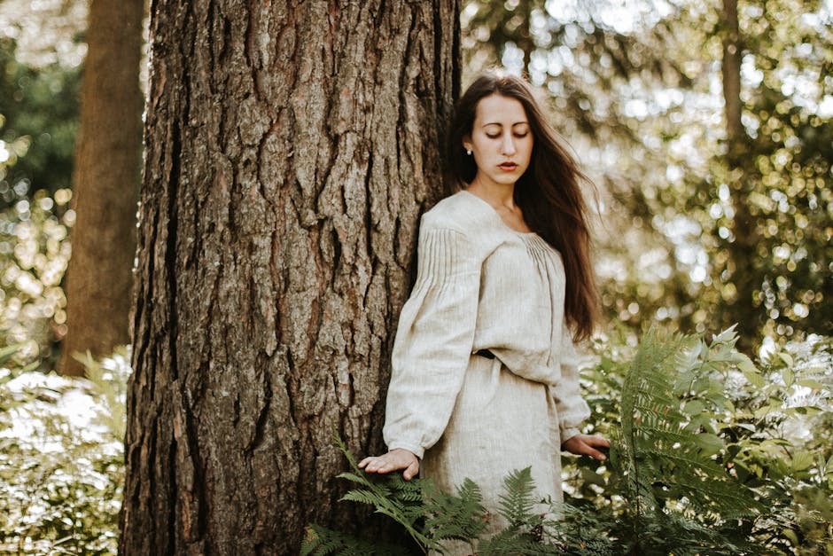 Woman in a flowing cream linen midi dress standing outdoors in summer sunshine