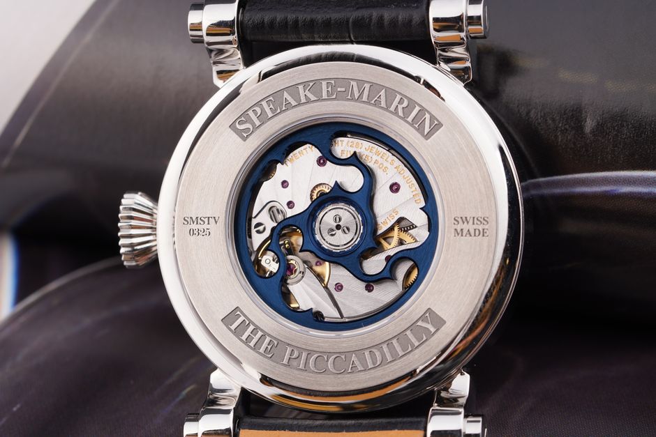 Close-up of an elegant Swiss dress watch with a white dial and leather strap resting on a marble surface