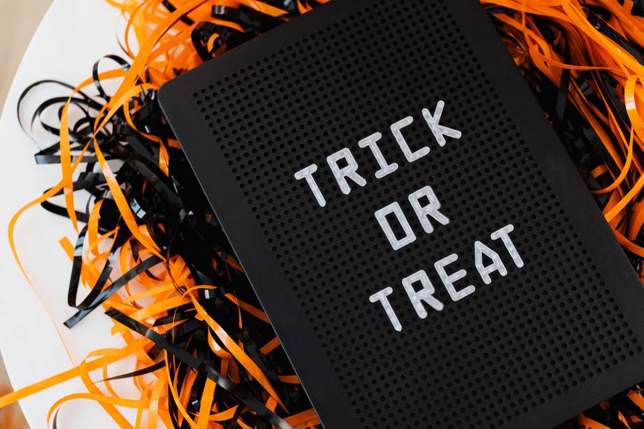 Close-up of a 'Trick or Treat' sign surrounded by festive orange and black streamers, perfect for Halloween decor.