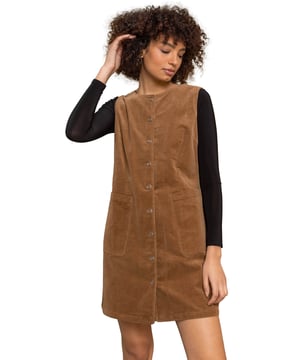 Corduroy Button Detail Pinafore Dress from Roman. Say hello to an instant style upgrade with this corduroy pinafore dress. Cut to flatter, this button through dress is finished with a round neck and a sleeveless body, making it great to layer over long sleeve tops this autumn. This cosy cord fabric is so timeless and great for the season, with front pockets for all of your essentials. Team with tights and boots for the office and go from desk to dinner by swapping your boots for heels.