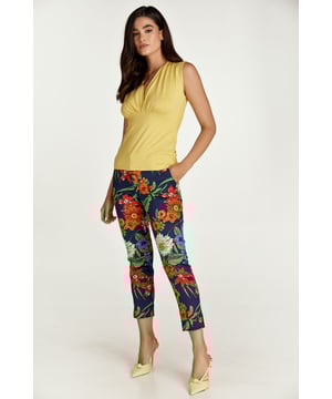 Estos pantalones cortos de largo 7/8 están confeccionados en tela de gabardina elástica floral en tonos de rojo, azul y verde. Hay una cinturilla de 5 cm con trabillas en el mismo tejido. Los pantalones se abrochan en la parte delantera con un botón blanco de material natural y una cremallera oculta blanca. A los lados hay bolsillos con aberturas diagonales. En el lado exterior del dobladillo hay una abertura redondeada. Estos pantalones son ecológicos.