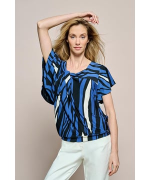 Ontdek de veelzijdige Conory print top, een perfecte keuze voor een heerlijk comfortabele en unieke zomertop. Met een trendy grafische vloeiende print in marineblauw en blauw met offwhite, straalt deze top speelse elegantie uit, ideaal voor de zomer. Deze stijlvolle damestop is verrijkt met unieke details. Let vooral op de mouwen, die een prachtige vlindervalling hebben en aan de binnenkant zijn gevoerd. Een unieke asymmetrische halslijn met een knoopdetail voegt een extra vleugje identiteit toe aan deze damestop. De onderkant van de blouse bevat een tailleband, wat zorgt voor een bloezend effect. De achterkant van de trendy damestop in marineblauw heeft ook een uniek detail, namelijk een unieke V-hals valling. De Conory print top is tevens ontworpen met een grafische naadverdeling, wat ervoor zorgt dat de top mooi om het bovenlichaam valt met een speelse twist. De hoogwaardige jerseykwaliteit biedt elasticiteit en zachtheid voor een moeiteloze draagervaring.