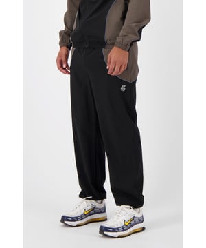 86% Nailon | 14% Spandex Ajuste relajado Cintura elástica Diseño bicolor con pierna ancha Logotipo reflectante en el lado izquierdo Dos bolsillos con cremallera Se puede combinar con la RFLCT Tracktop
