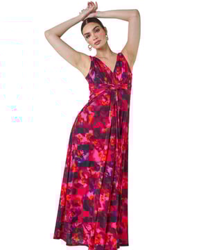 Floral Knot Front Maxi Dress from Roman. Release your inner goddess in this luxe Ariella collection maxi dress. The elegant sleeveless design showcases a flattering fit and flare silhouette with a v-neckline and a stunning v-back detail. Adorned in a beautiful floral print, this sophisticated dress is perfect for Spring Summer events. The twist detail at the waistline adds a touch of glamour, while the gathered waist and concealed zip fastening ensure a perfect fit. Style with strappy heels and a fascinator for a wedding reception or add a clutch bag for a formal dinner at the captain's table!