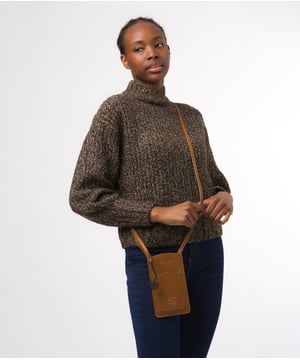 The 'Siren' from Conkca London is handcrafted from genuine leather for a beautiful finish. This open-top phone bag is the perfect way to keep your phone on your person whilst keeping your hands free. The interior is lined with natural and untreated 100% cotton. Includes a cotton-lined slip pouch on the front and two card slots on the rear, ideal for maintaining an organised bag. Comes with an adjustable leather strap with a drop length of 70cm, alongside gold metal fittings. Adorned with the iconic Conkca logo and charm.