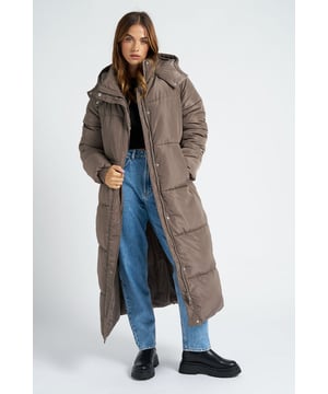 Model is 5'6 and wears a size S. The maxi length offers enhanced coverage and warmth, ensuring you're shielded from the elements in ultimate style. The puffer construction provides the perfect balance of insulation and comfort, allowing you to brave cold temperatures while maintaining your fashion-forward sensibilities.