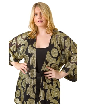 Curve Floral Foil Print Kimono from Roman. Be the star of the show at your next event with our glamorous Curve foil kimono. The woven fabric is adorned with floral foil print for a sparkling finish, perfect for special occasions. The classy edge-to-edge opening and 3/4 length sleeves add a sophisticated touch, while this kimono finishes around knee-length. Pair this kimono with wide-leg trousers and heeled boots for a stylish outfit that will turn heads wherever you go!