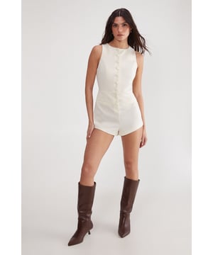 Sleek tailored playsuit for a polished look
        High neckline and sleeveless design for a professional appearance
        Fitted waist to accentuate your silhouette
        Striking open back with elegant tie detail
        Short length perfect for warmer office environments
    
    Make a statement in the boardroom with this chic Essentials Tailored Playsuit from NastyGal. This versatile piece seamlessly blends sophistication with contemporary style, making it an ideal choice for the modern professional. The high neckline and sleeveless cut offer a refined look, while the tailored fit flatters your figure. The playsuit's short length adds a touch of modernity, perfect for navigating warm office spaces with ease. For a polished workwear ensemble, pair it with a structured blazer and classic court shoes. Alternatively, dress it down for after-work drinks by swapping the blazer for a lightweight cardigan and adding some statement jewellery. The unexpected open back with its elegant tie detail adds a subtle hint of allure, ensuring you transition effortlessly from day to evening events.