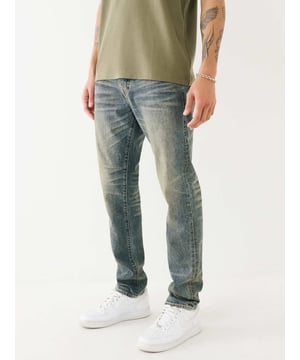 Upgrade your denim with the Rocco Single Needle Flap Skinny Jean. This pair of men’s skinny jeans feature a faded wash, zip fly, whiskering, belt loops, and gold Single Needle stitching. Finished with burnished hardware, horseshoe detailing on the back flap pockets, and a shorter 32” inseam. 