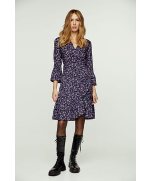Deze wikkeljurk met bloemenprint is gemaakt van geweven viscose. Hij heeft een V-hals en 3/4 klokmouwen. Deze wikkeljurk heeft een das aan de linkerkant die door een gat aan de rechterkant gaat en die met de rechter das aan de zijkant of aan de achterkant wordt vastgemaakt. In de zoom zit een ruche van ongeveer 15 cm