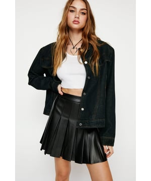 Leather weather. This stylish leather-look mini skirt is made with ultra soft faux leather that is silky smooth to the skins touch. Sitting comfortably high on the waist, the skirt features a thick waist band that cinches in the stomach creating a flattering hourglass silhouette. The skirt features heavy pleating across the front and back, channeling the iconic preppy 90s style. Pair with a simple white tank, sneakers and varsity jacket for a laidback transeasonal look. OR, add some drama with a =n oversized black shirt and your strappiest heels. Easy to Clean Wipeable Faux Leather  Full Coverage High Waist  Restriction-Free Mini Length  Tailored Pleat Front Detail Sleek Soft Faux Leather Fabric Accessible Zip Closure Model wears a size M (US size 6/UK size 10).