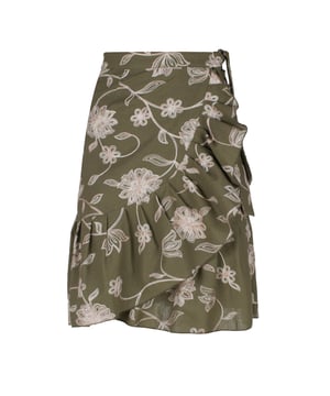 Esta falda cruzada floral verde oliva está confeccionada en un tejido de mezcla de lino y bordada con un hilo de dos tonos en crudo y beige. La falda se abrocha con una corbata de 4,5 cm del mismo tejido que pasa a través de un agujero en la costura lateral, justo debajo de la cintura. La falda tiene un ribete de volantes de 26 cm por todas partes. Tiene un estilo sutil con una silueta de línea A y llega hasta la rodilla.