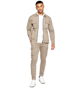Enzo Cargo-outfitset voor heren. Lange mouwen, ritssluiting, kraag, cargo-overshirt. Twee platte vrachtzakken aan de voorkant met klittenbandsluiting. Twee zijzakken. Gestikte randen op mouwen en zoom. Set aangevuld met cargobroeken. Normale pasvorm, rechte pijpen, enzymenwassing. Ontwerp met 5 zakken. 2 zijzakken, 2 cargozakken met klittenbandsluiting. Enkele achterzak. Elastische tailleband met verstelbaar trekkoord