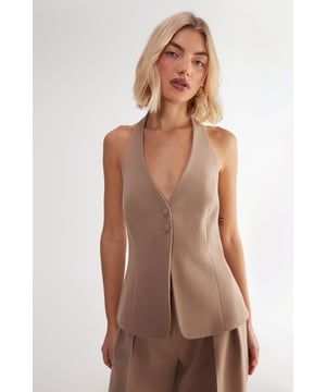 Sleek tailored vest with button front closure
        Plunging V-neckline for a sophisticated look
        Halter-style design with open back
        Single decorative button detail at the waist
        Versatile piece for layering or wearing alone
    
    Elevate your workwear wardrobe with this chic tailored vest from NastyGal's Essentials collection. Perfect for the modern professional, this sleek piece offers a contemporary twist on classic office attire. Style it over a crisp white shirt and pair with tailored trousers for a polished look that commands attention in the boardroom. For a more relaxed yet refined ensemble, layer it over a lightweight turtleneck and team with high-waisted wide-leg trousers. The vest's versatility shines through as day turns to night - simply pair it with sleek cigarette trousers and statement earrings for after-work drinks. With its ability to transition seamlessly from desk to dinner, this tailored vest is a must-have addition to any fashion-forward professional's wardrobe.