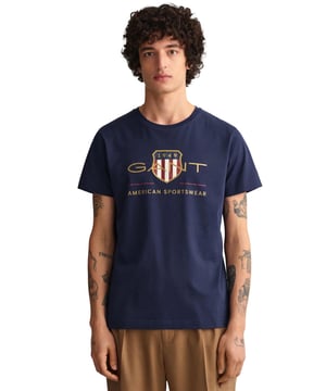 Mens Designer Gant Archive Shield T-Shirts feature Short Sleeves and a Crew Neckline. Gant Logo Printed on chest. Crafted With 100% Cotton, these Lightweight and breathable Regular Fit T-shirts are Machine Washable.