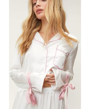 Early nights pending. Feel luxe in our pajama pants set, with button fastenings, an ultra comfortable relaxed fit, and ruffle trims. Style them with slippers and a robe for a look that will take you from movie nights to lazy mornings. Satin Contrast Piping Tie Sleeve Pajama Pants Set Feminine Ruffle Design Unique Tie Sleeve Details Flattering Relaxed Fit Button Up Pajama Shirt Comfortable High Waist Pajama Pants Model wears a size M (US size 6/UK size 10).