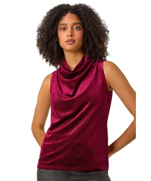 Glitter Velvet Cowl Neck Stretch Top from Roman. Wrap up in style with this our cowl neck velvet top, perfect for the Winter season. The cowl neckline adds an elegant touch, while the sleeveless design is ideal for layering under a jacket for extra warmth. Falling below the hip for a flattering tunic fit. Crafted from sumptuous velvet fabric, this top is luxurious and soft to the touch. Pair with pleather trousers and heeled boots for a sophisticated and party-ready outfit!